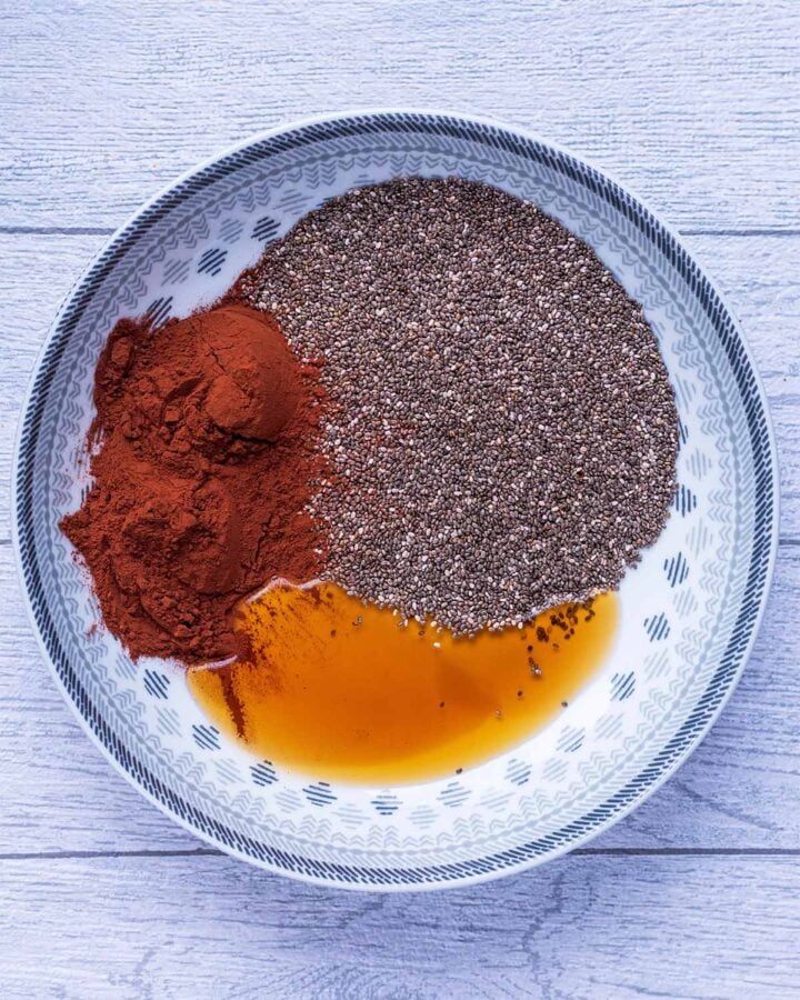 A large dish containing chia seeds, cocoa powder, maple syrup and vanilla.