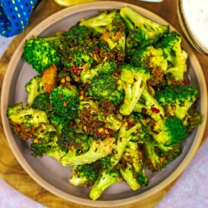 A plate of crispy air fryer broccoli florets with chilli flakes on top.