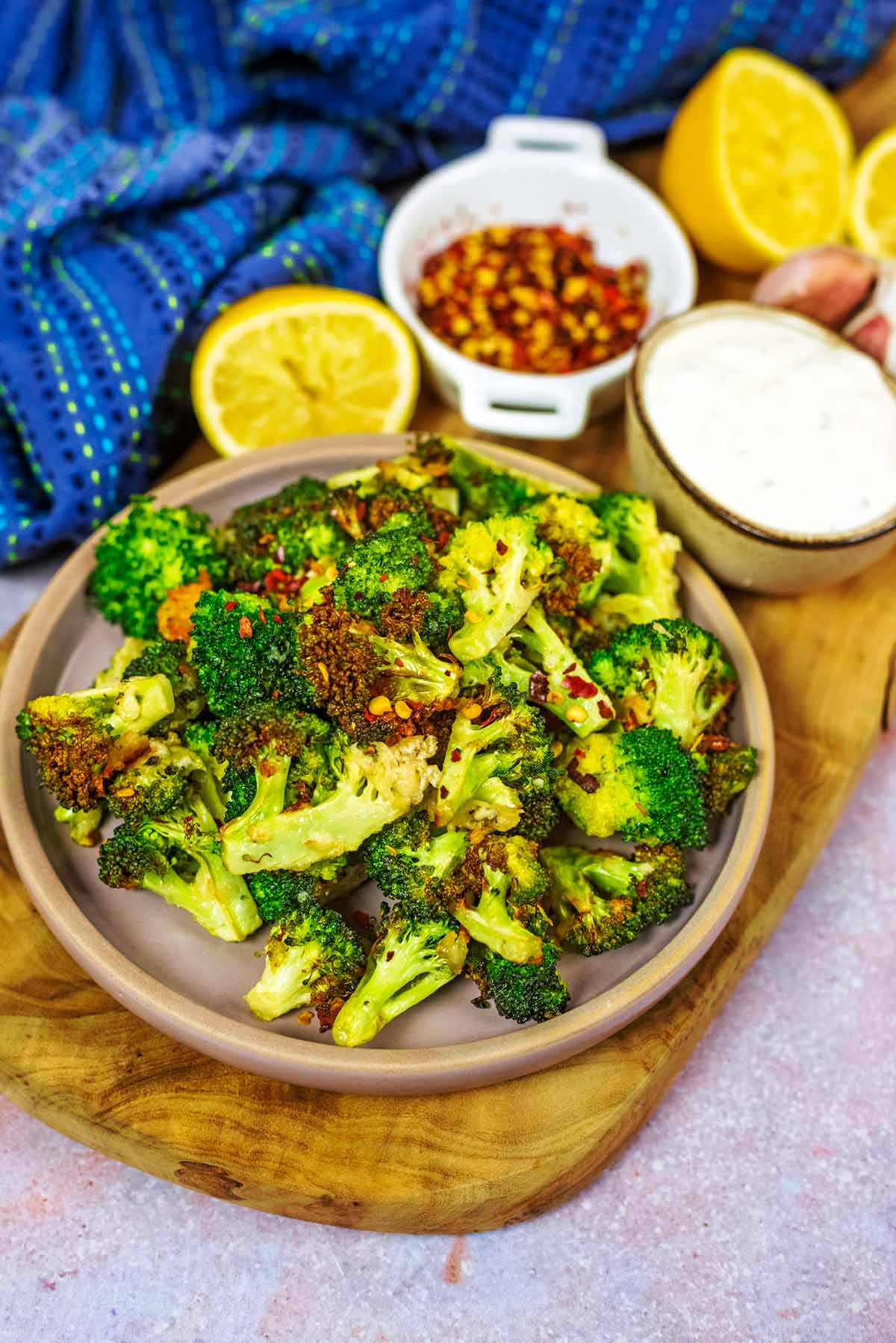 A wooden serving board with a plate of cooked broccoli on it.