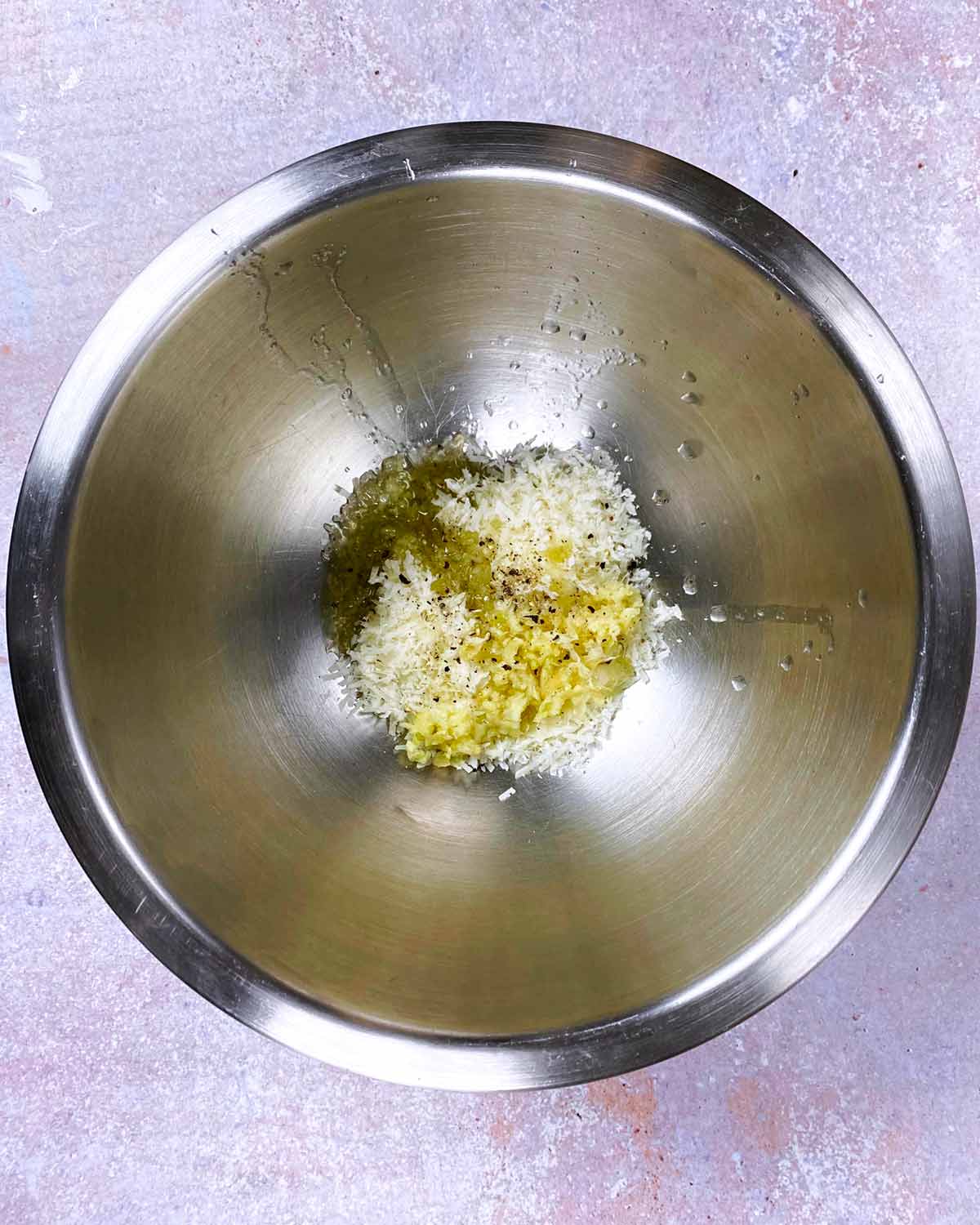 A bowl with crushed garlic, oil, salt and pepper in it.