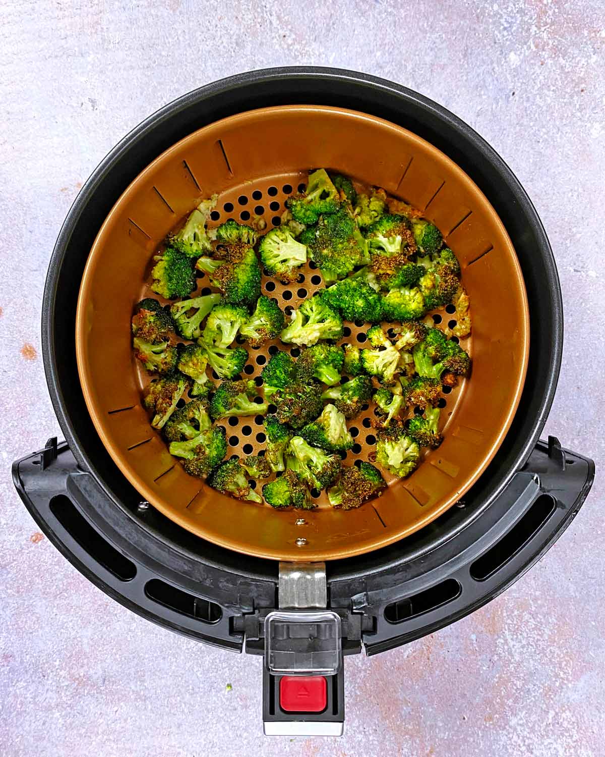 Crispy broccoli in an air fryer basket.