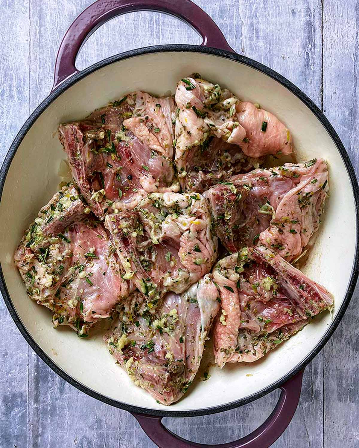 Herb covered chicken thighs in a shallow baking dish.