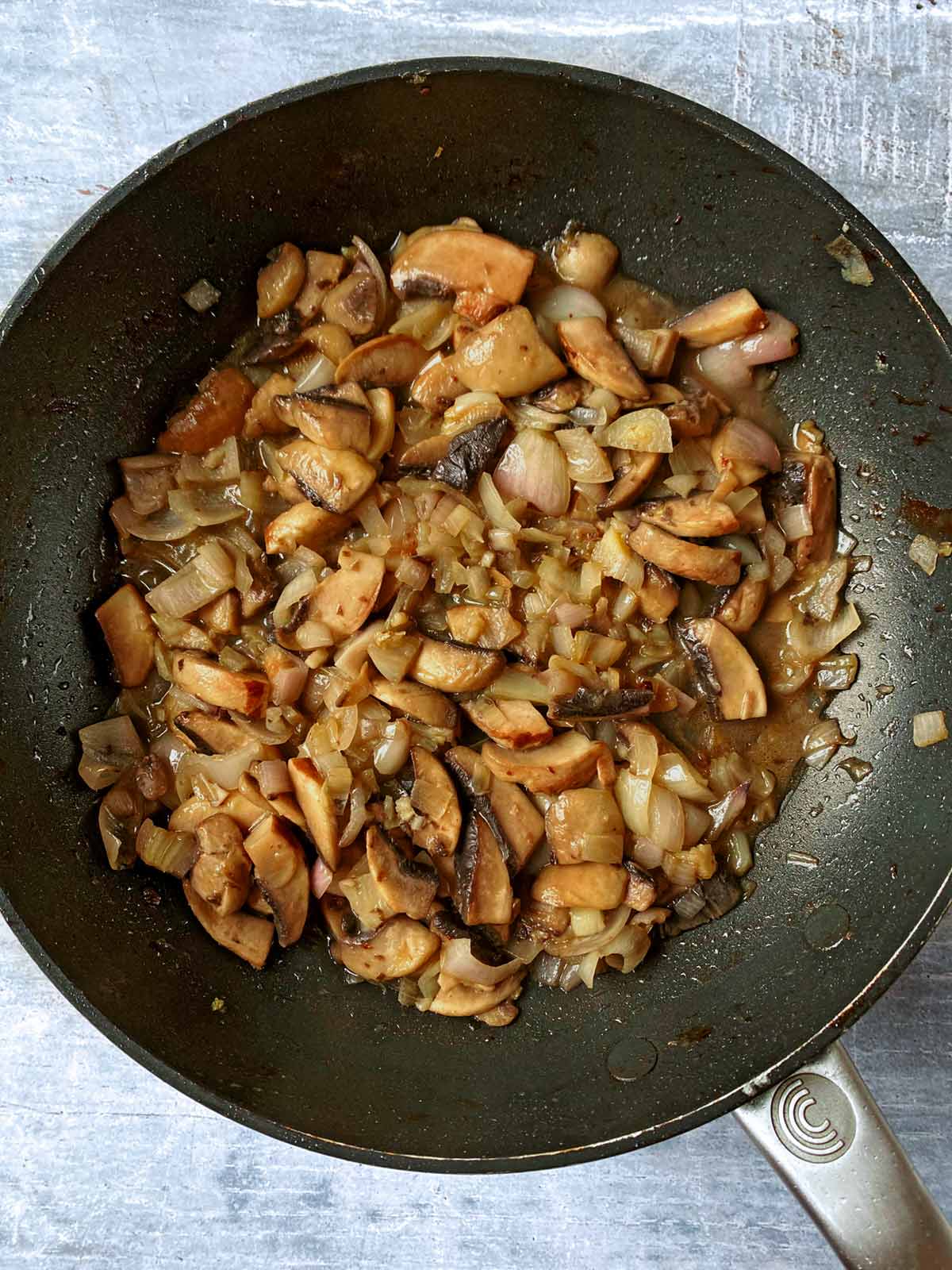 Chopped shallots and mushrooms cooking in a frying pan.