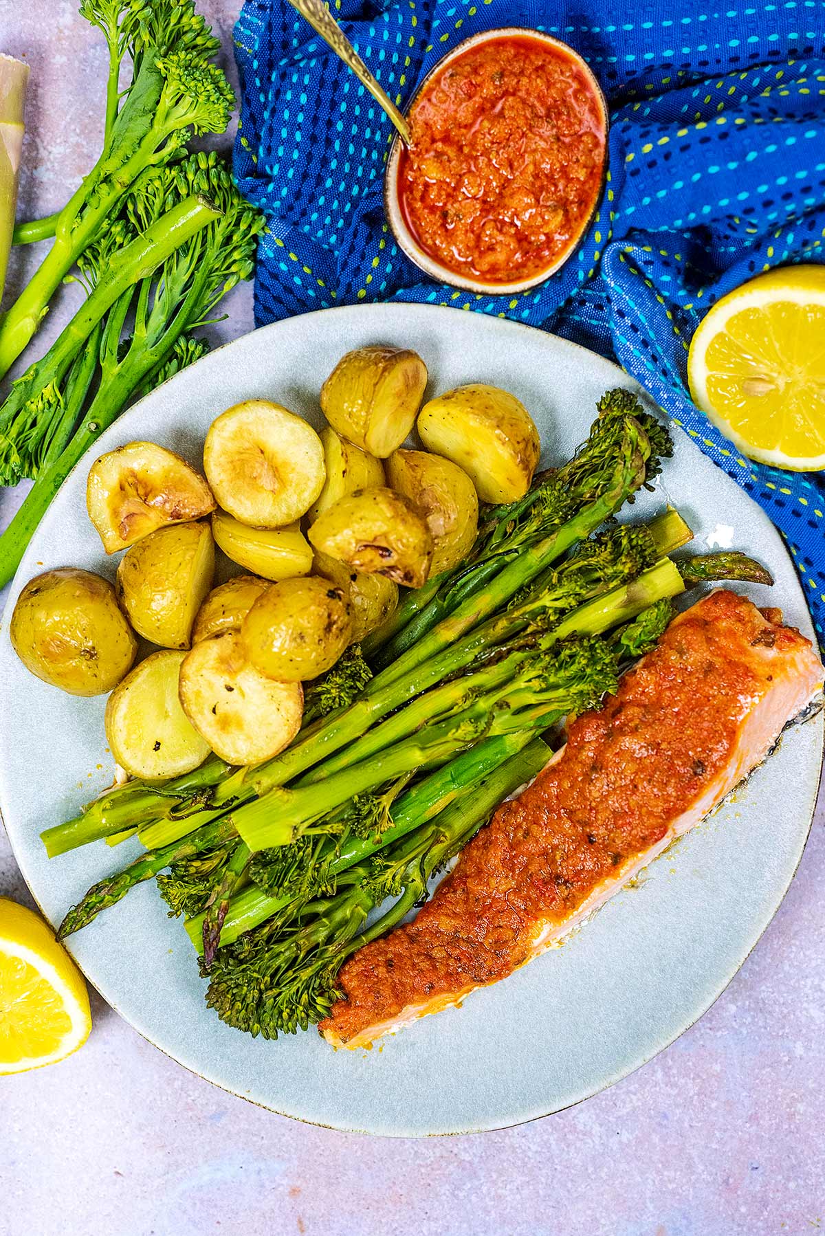 A plate of smothered salmon, asparagus, broccoli and potateos.