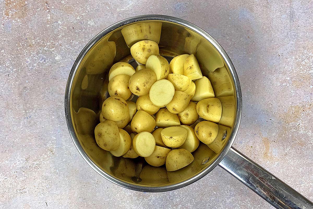A saucepan containing uncooked baby potatoes.