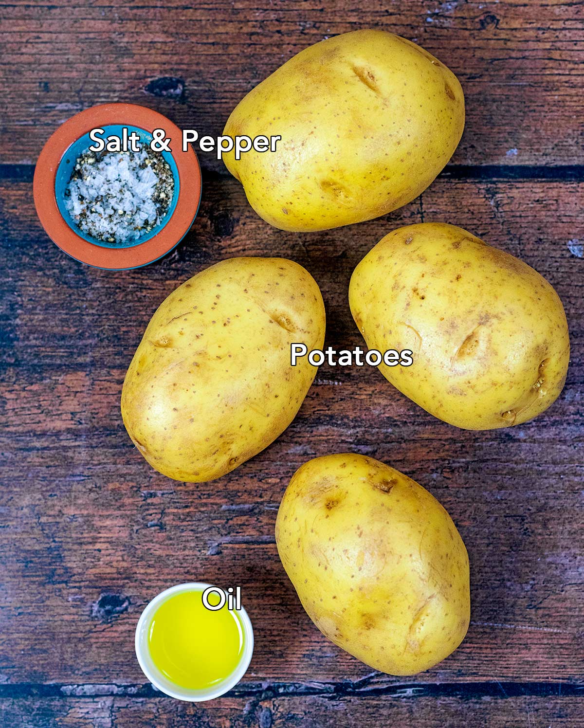 Four potatoes, a pot of seasoning and a small bowl of oil on a wooden surface with text overlay labels.