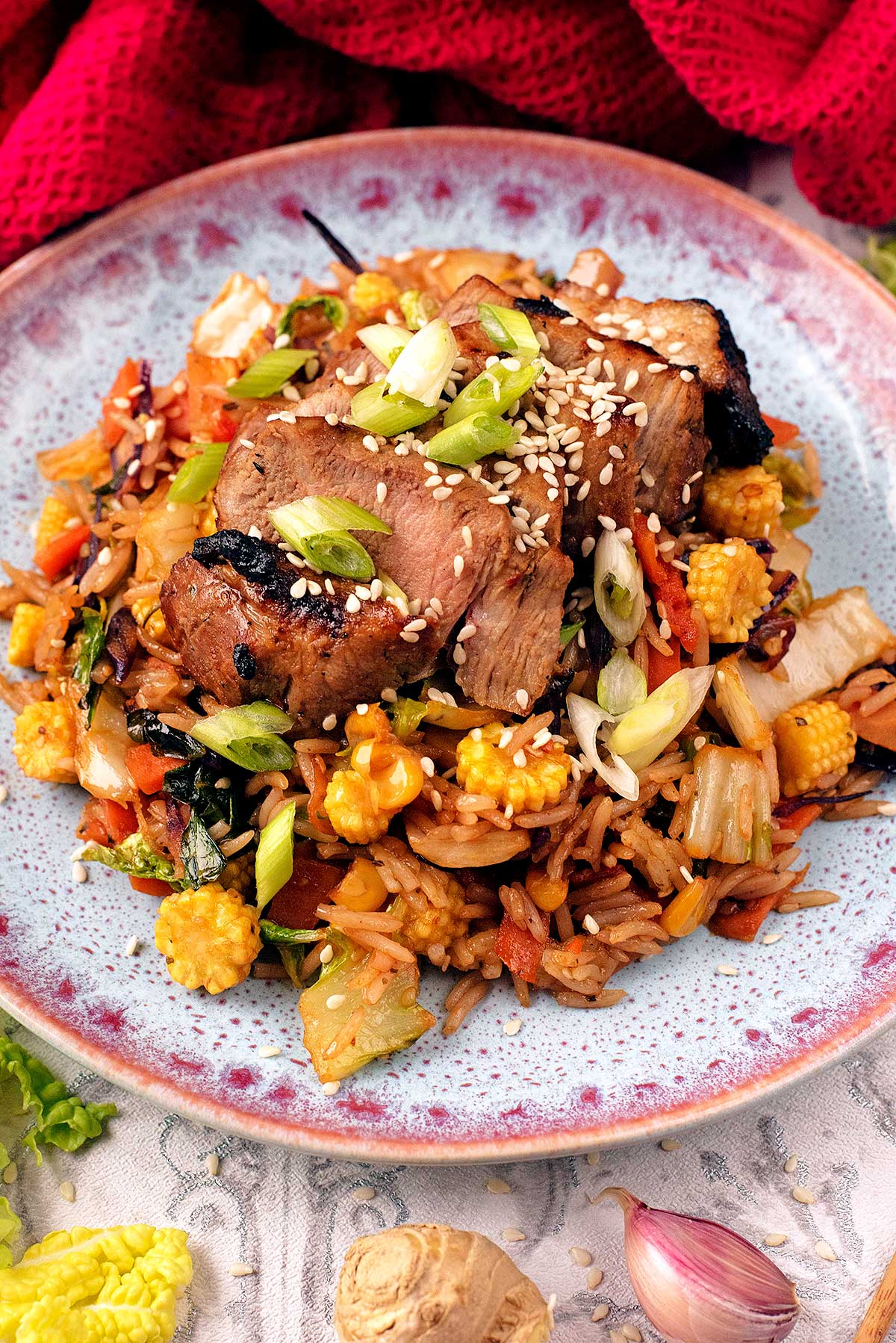 A stir fry dish made with vegetables and pork, on a round blue plate.