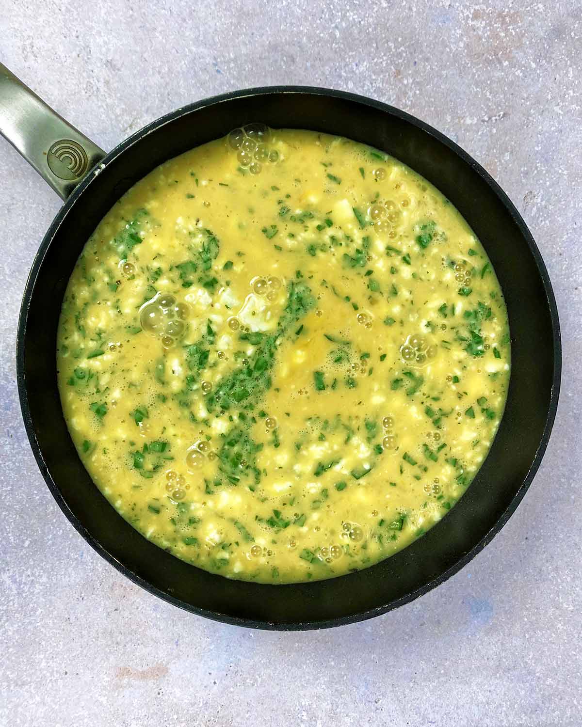 The egg mixture poured into the pan of cooked courgettes.