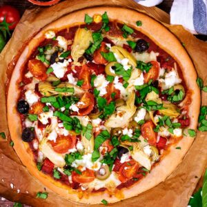 Greek Pizza on a square of baking paper.