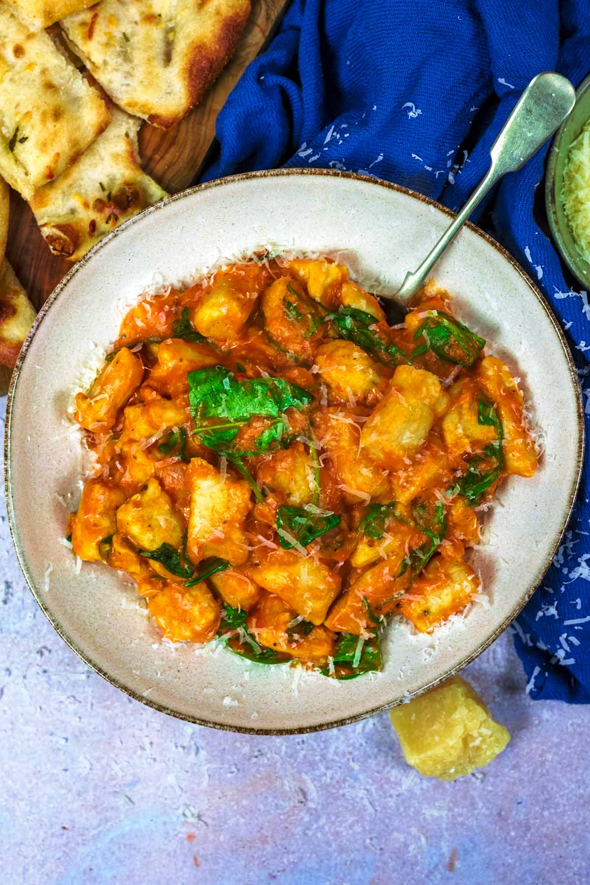 A bowl of gnocchi in a tomato sauce with a spoon.