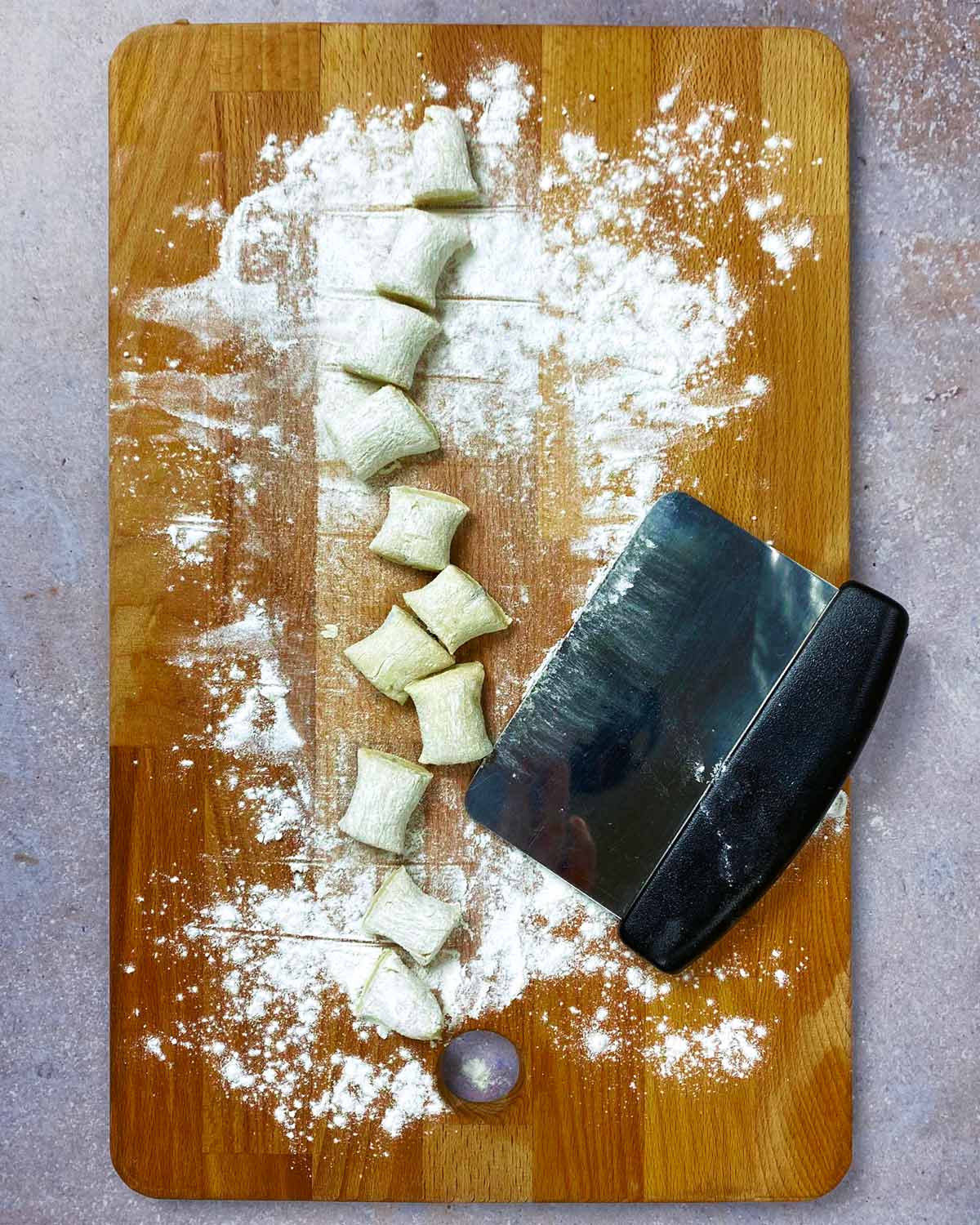 A chopping board with cut gnocchi on it.