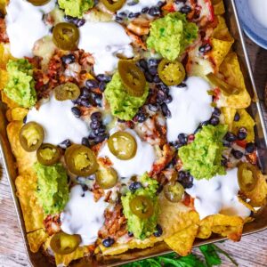 Loaded chicken nachos on a large metal baking tray.