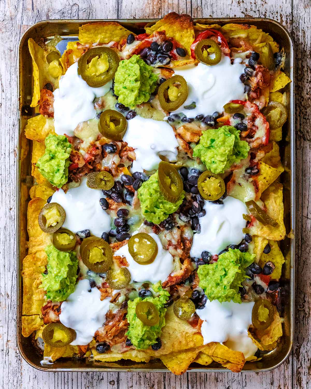 Nachos topped with sour cream, guacamole and jalapenos.