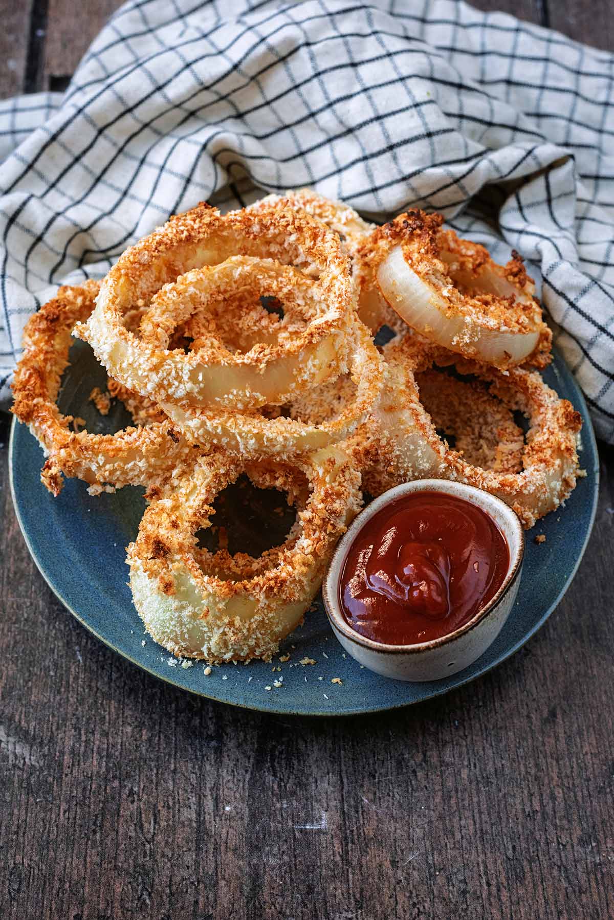 Baked breaded onion rings on a blue plate.