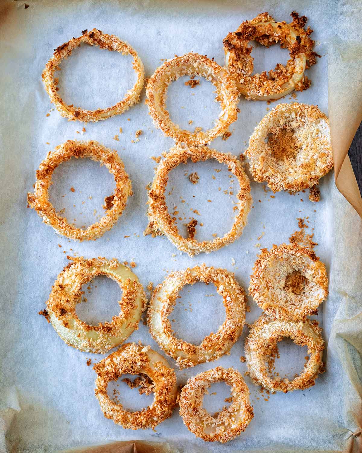 Cooked breaded onion rings on a baking tray.