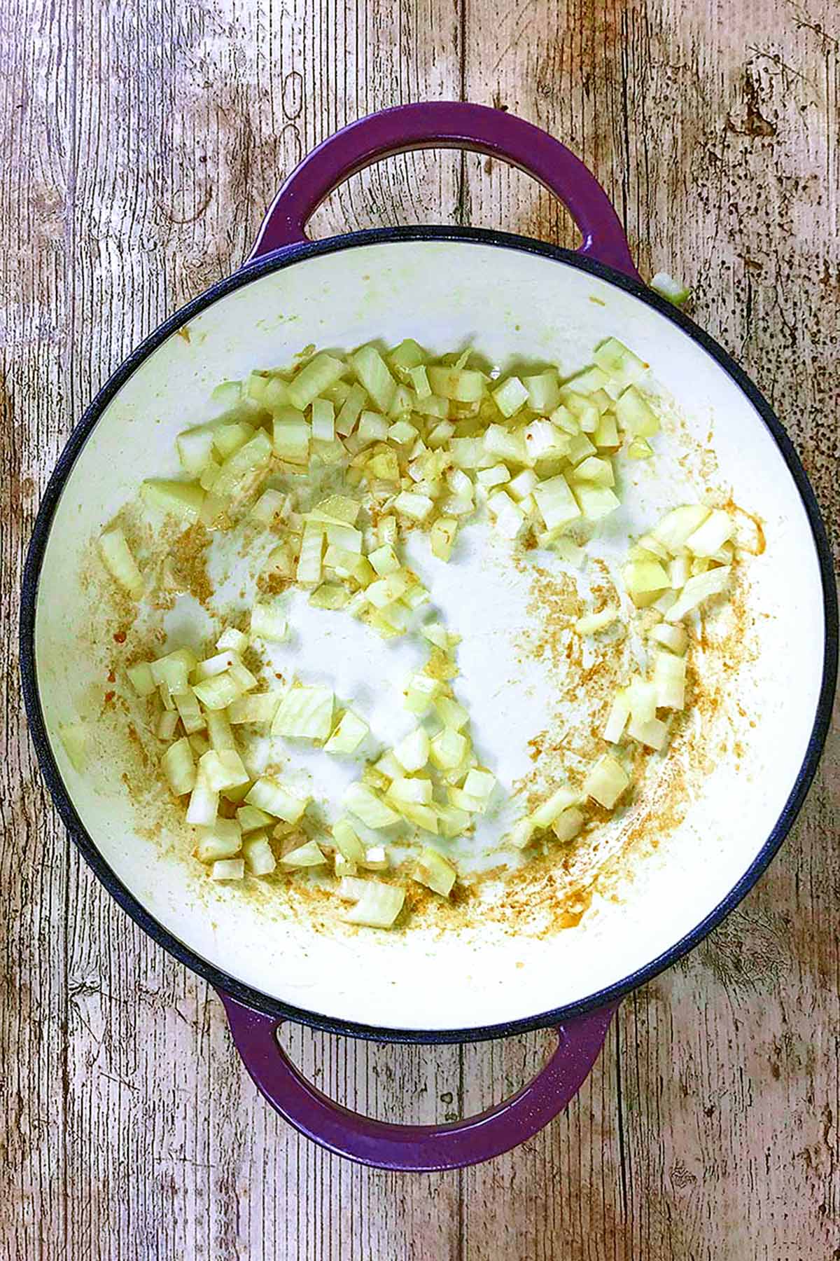 Chopped onions sautéing in a shallow pan.