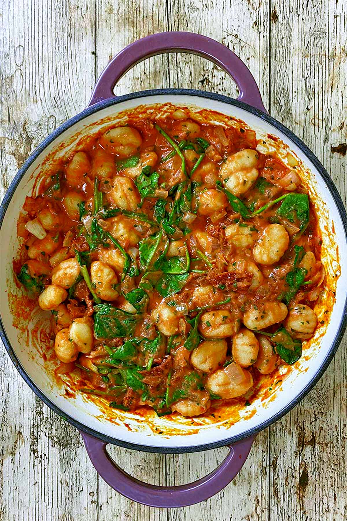 Gnocchi and spinach cooking in a creamy tomato sauce.
