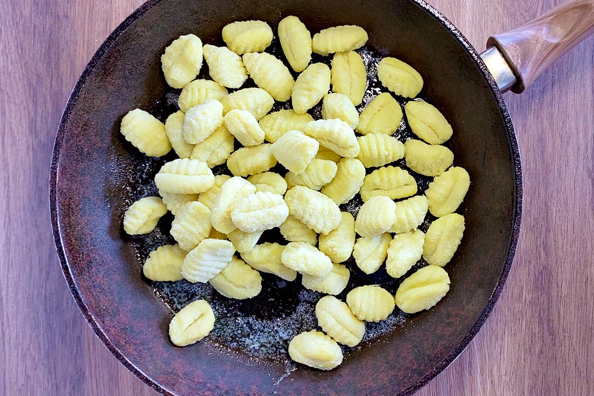 Gnocchi cooking in a frying pan.