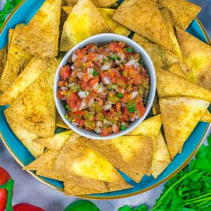 Air fryer tortilla chips on a plate with a bowl of salsa.