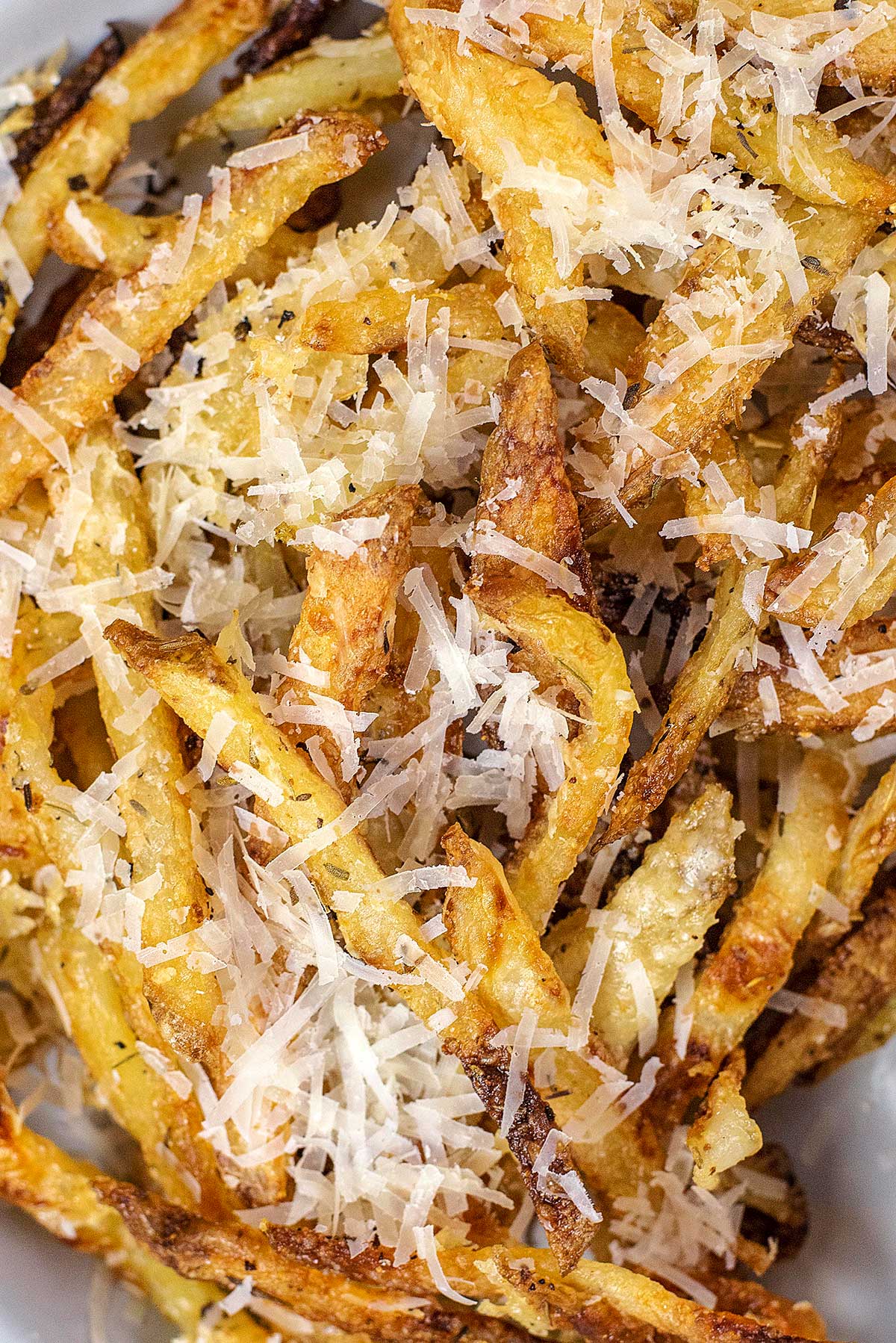 Cooked fries covered in grated Parmesan.