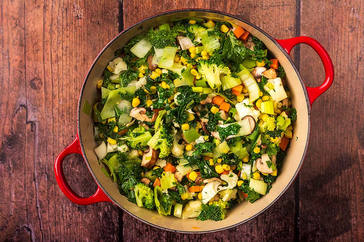 A large cooking pot full of chopped vegetables.