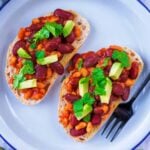 Two slices of Mexican Beans on sourdough toast, topped with avocado