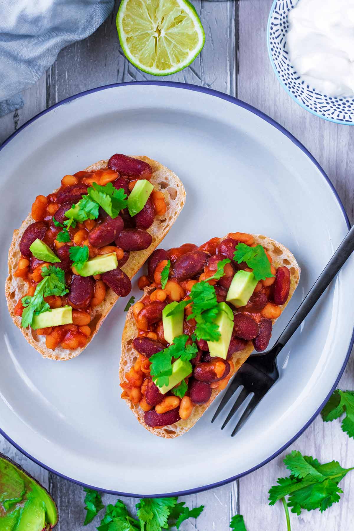 Two slices of toast topped with beans and chunks of avocado.