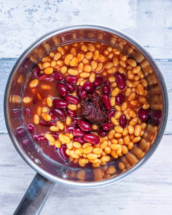 A saucepan containing baked beans. kidney beans and chipotle paste.