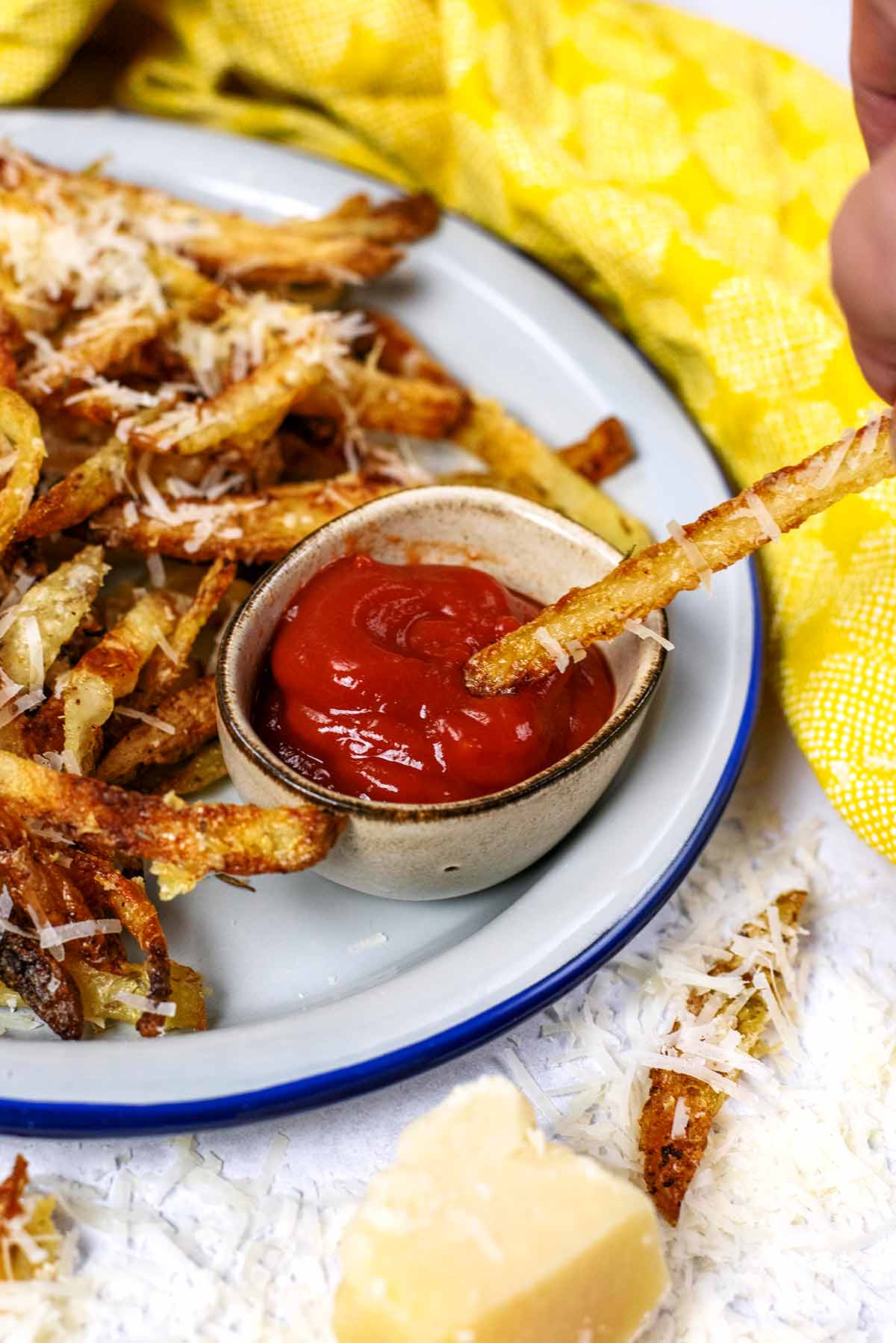A potato fry being dipped into some ketchup.