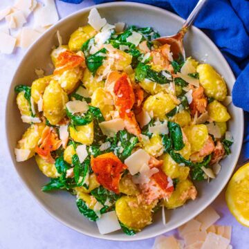 A bowl of 10 minute salmon gnocchi with a spoon.