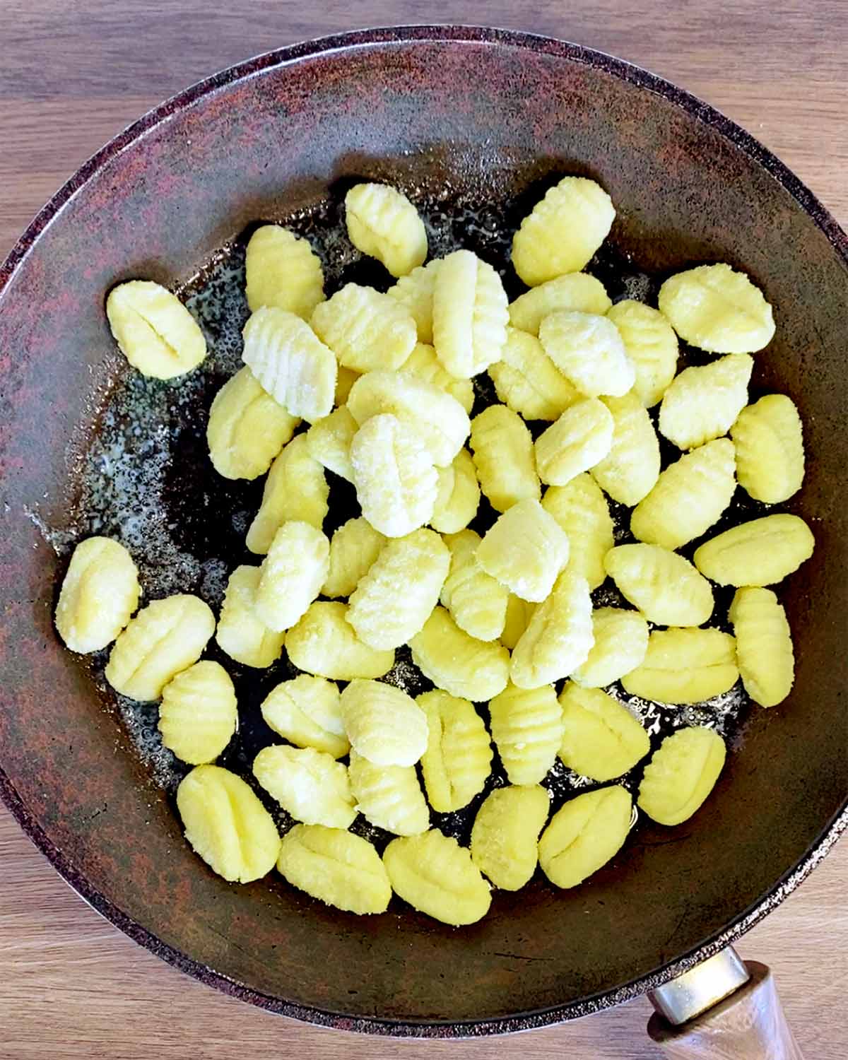 Gnocchi cooking in a frying pan.