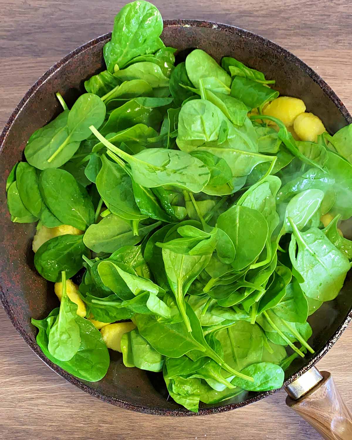 Spinach added to the pan of gnocchi.