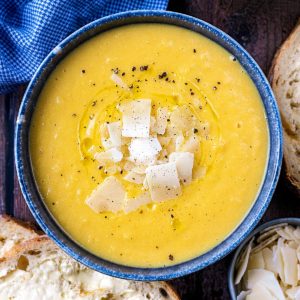 Creamy vegetable soup topped with Parmesan shaving and black pepper.