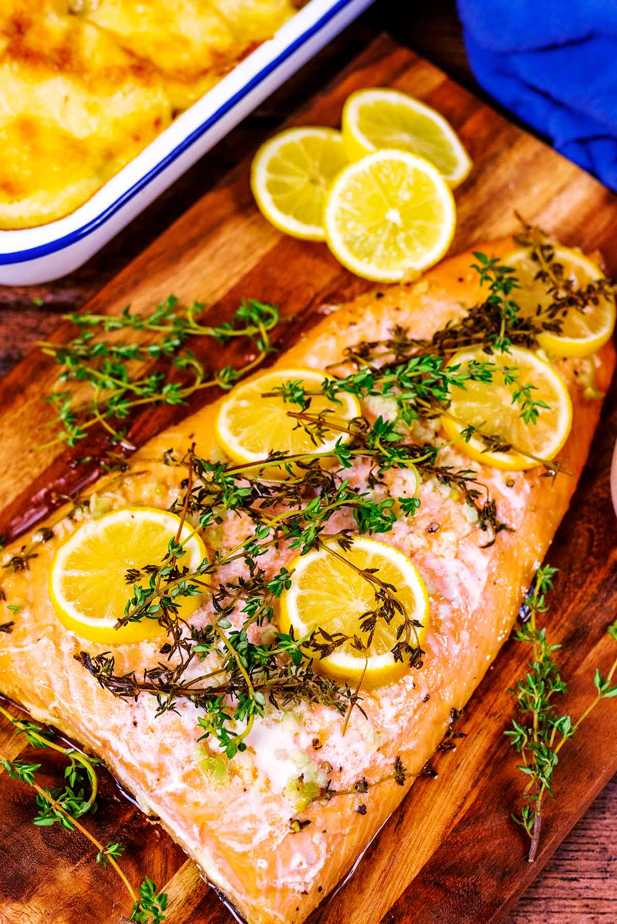 Baked salmon on a board in front of a tray of mashed potatoes.