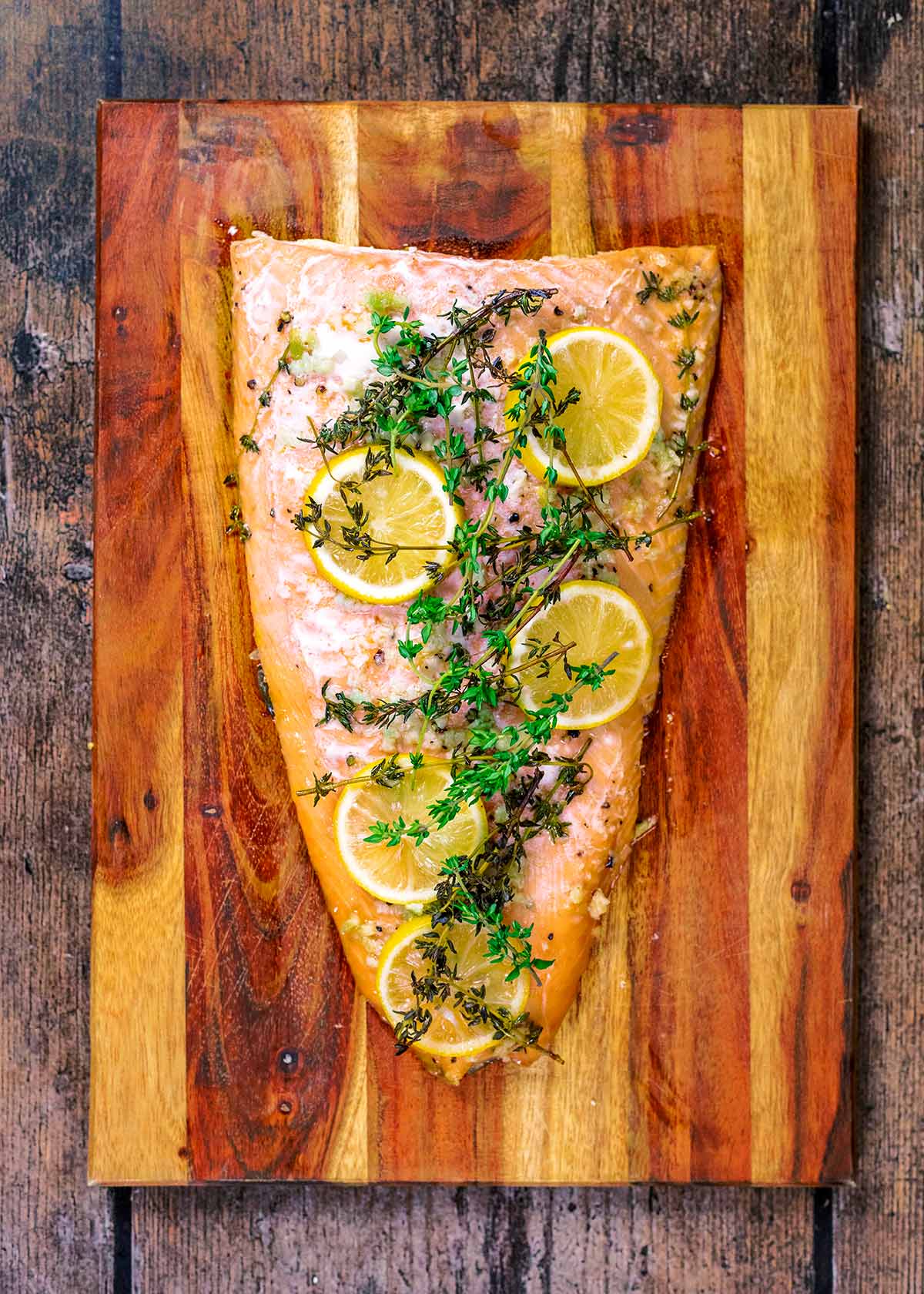 A cooked side of salmon on a wooden board.