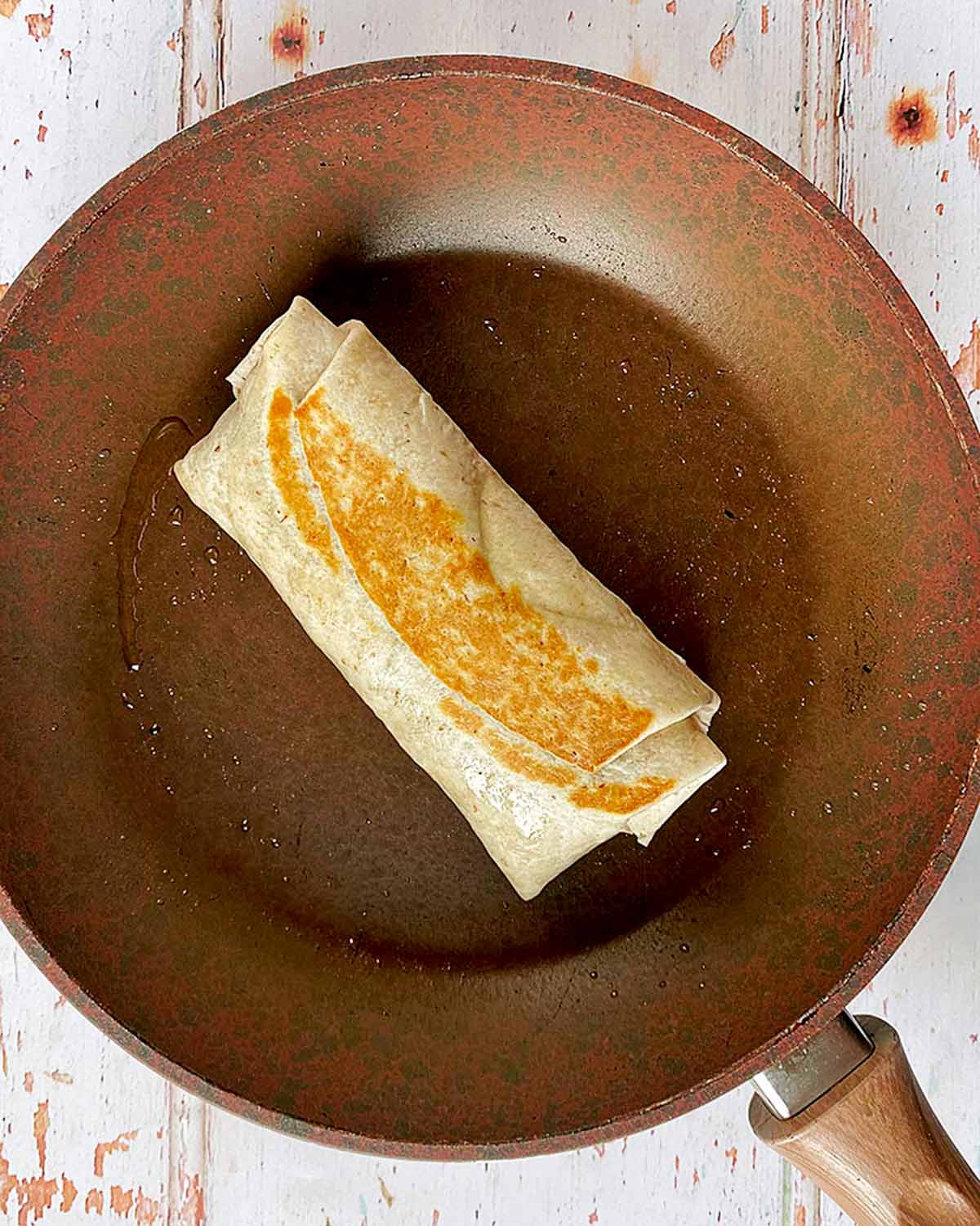 A burrito frying in a pan.