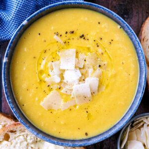 Creamy vegetable soup topped with Parmesan shaving and black pepper.