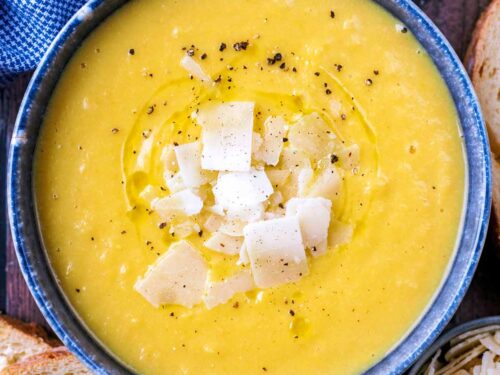 Creamy vegetable soup topped with Parmesan shaving and black pepper.