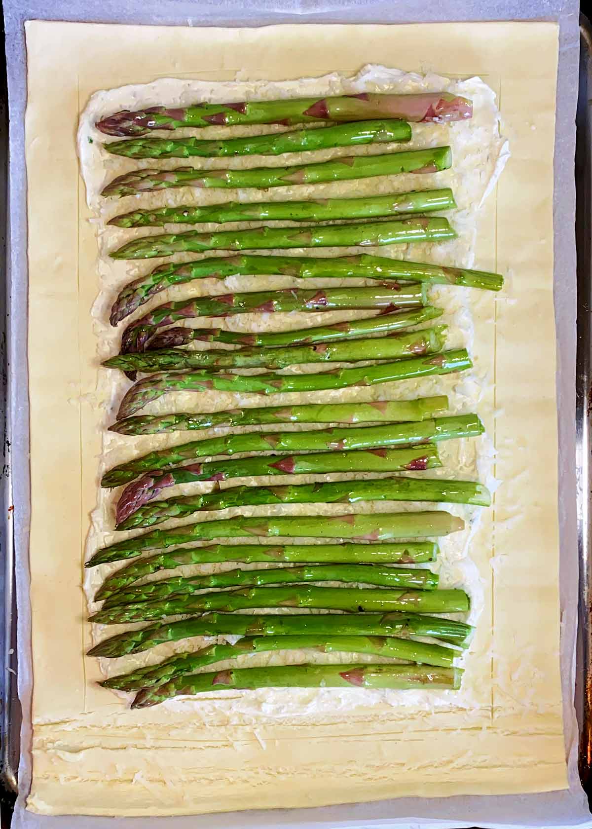 Asparagus arranged in a row on top of the cheese.