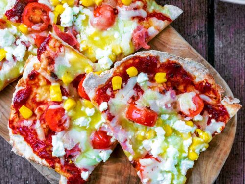 Slices of flatbread pizza on a wooden board.