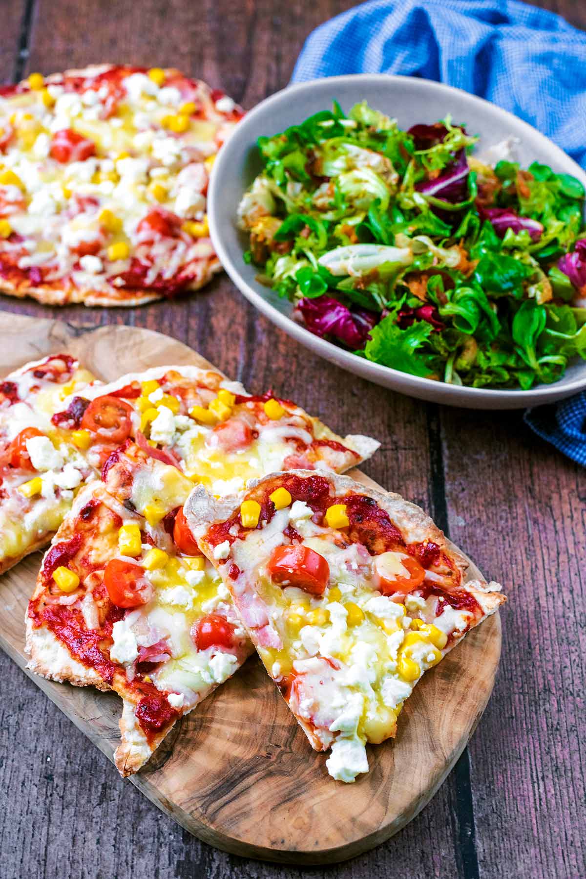 Slices of pizza in front of a whole pizza and some salad.