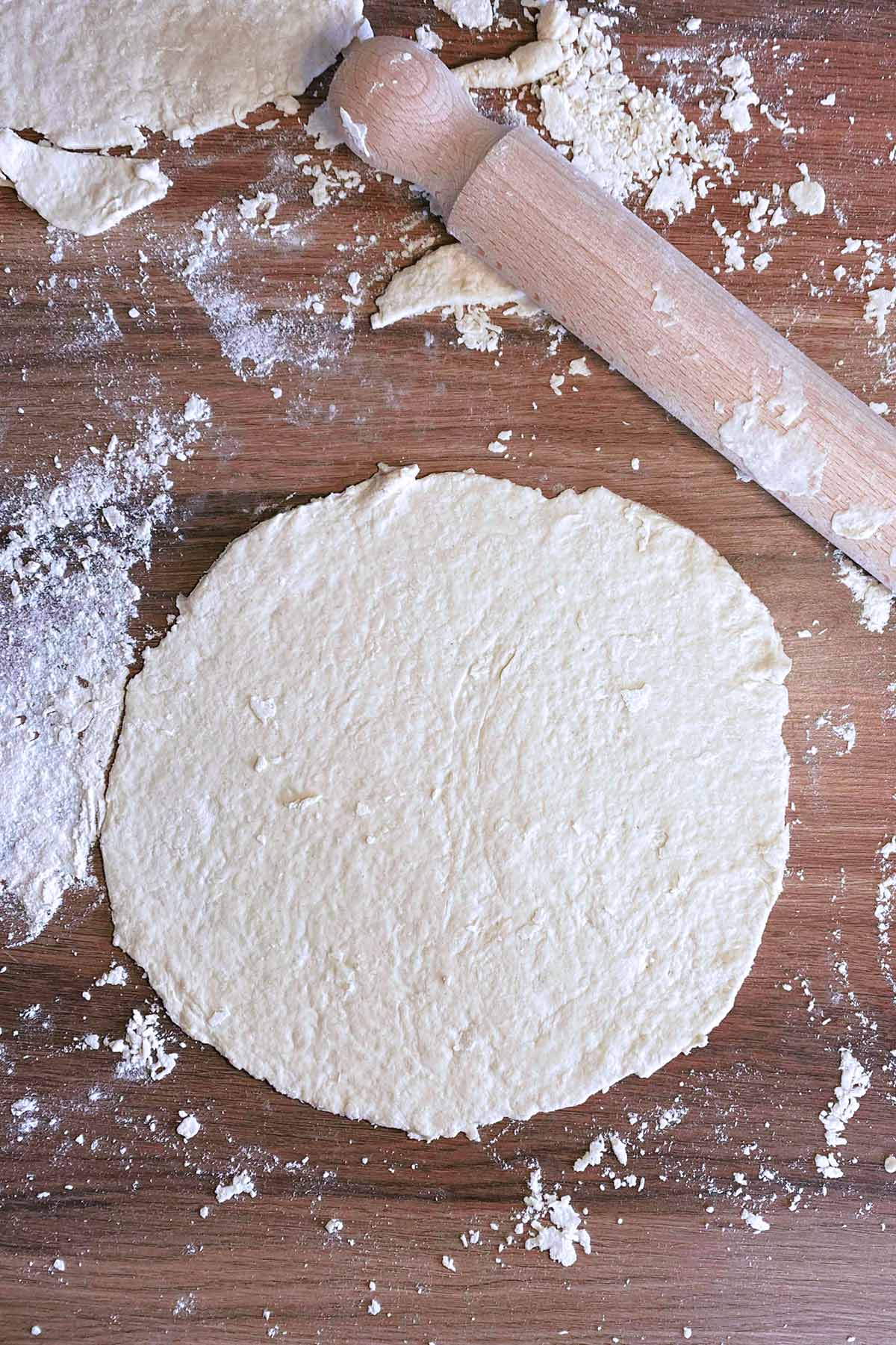Dough rolled out into a circle on a floured work surface.