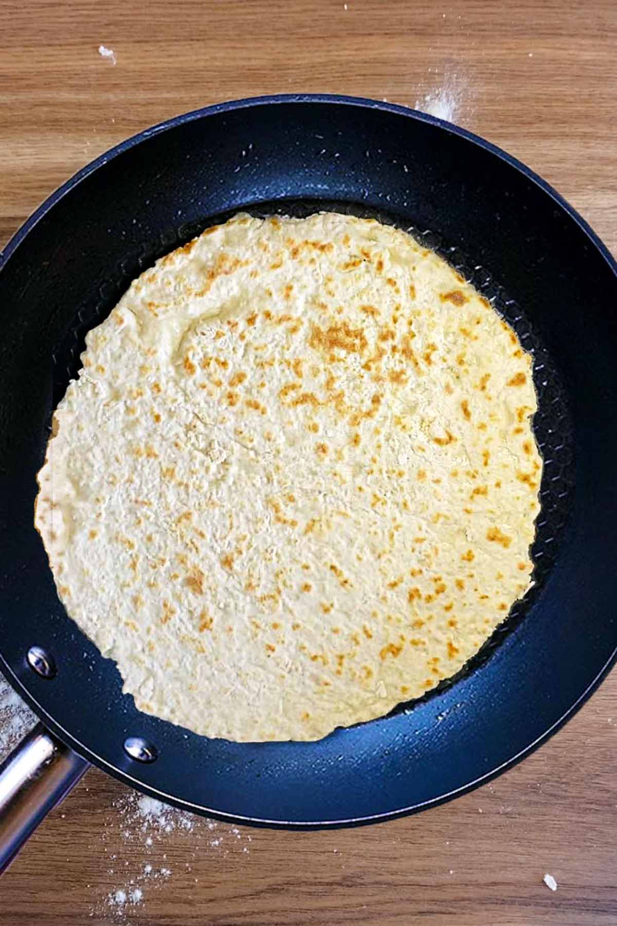 A flatbread cooking in a frying pan.