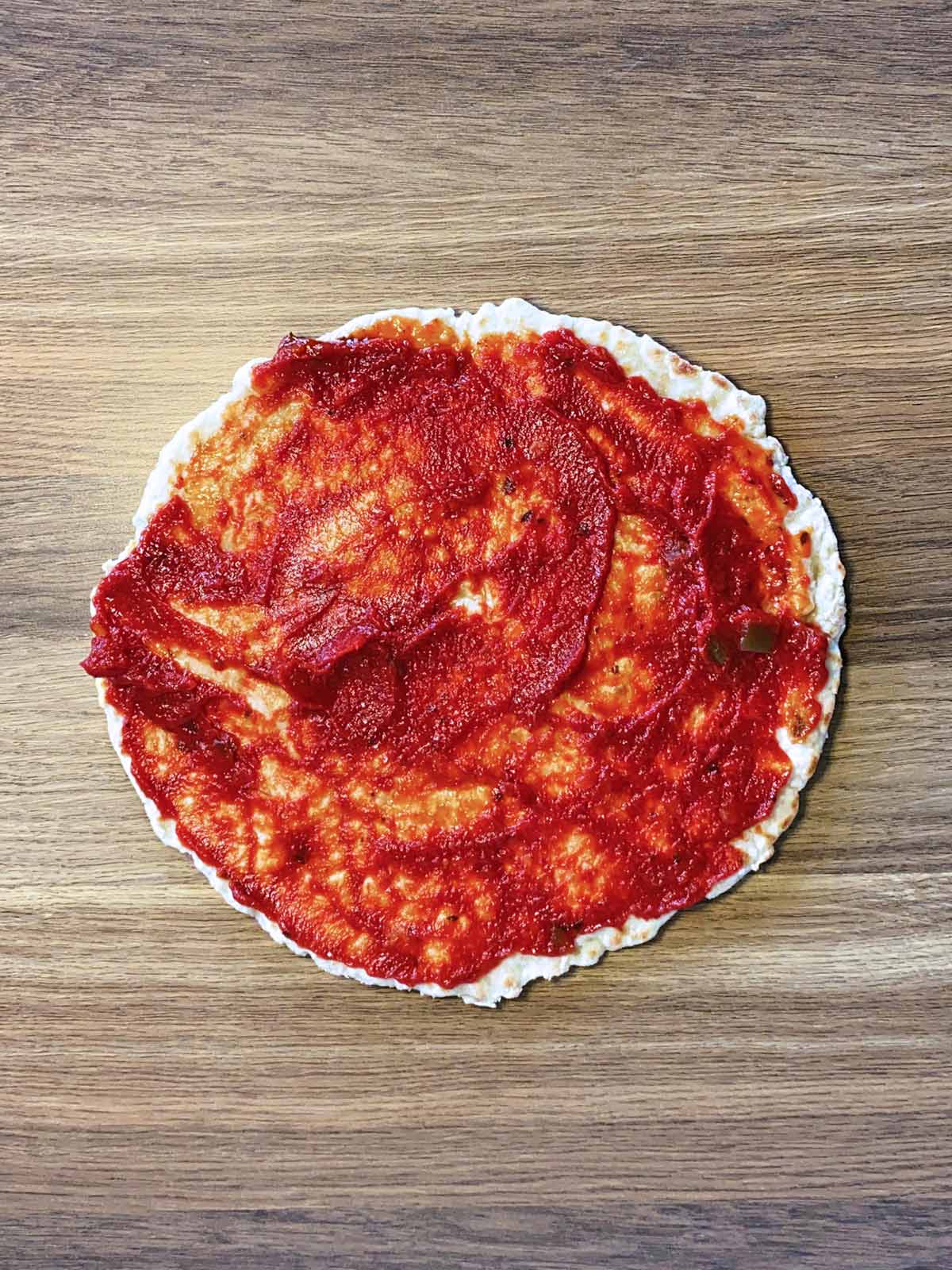 Pizza sauce spread over the cooked flatbread.
