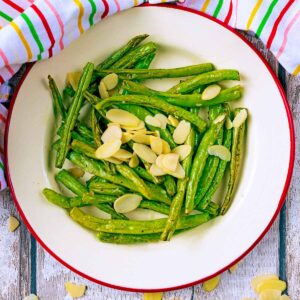 A plate of Garlic Green Beans topped with flaked almonds.