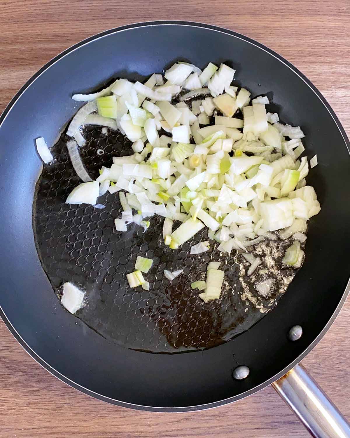 A frying pan with chopped onions sauteing in it.