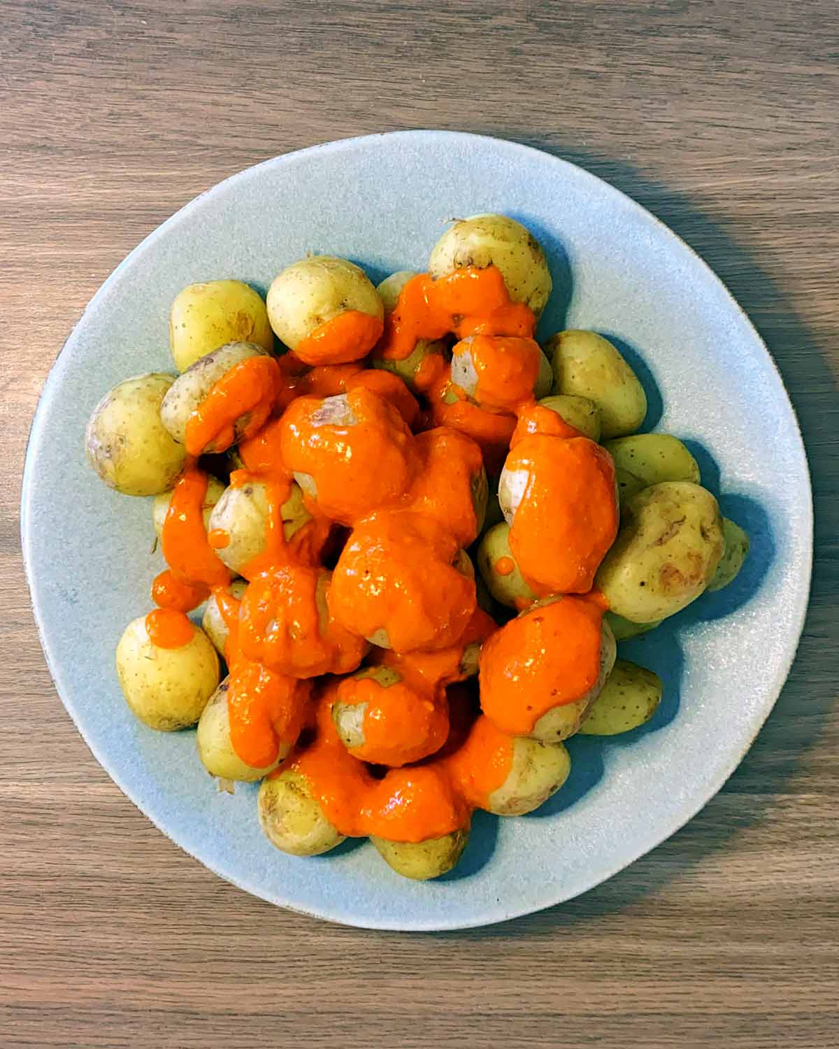 Cooked new potatoes on a plate covered in mojo picon sauce.