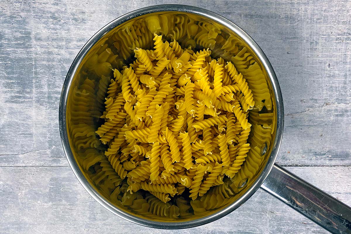 A saucepan containing uncooked fusilli pasta.