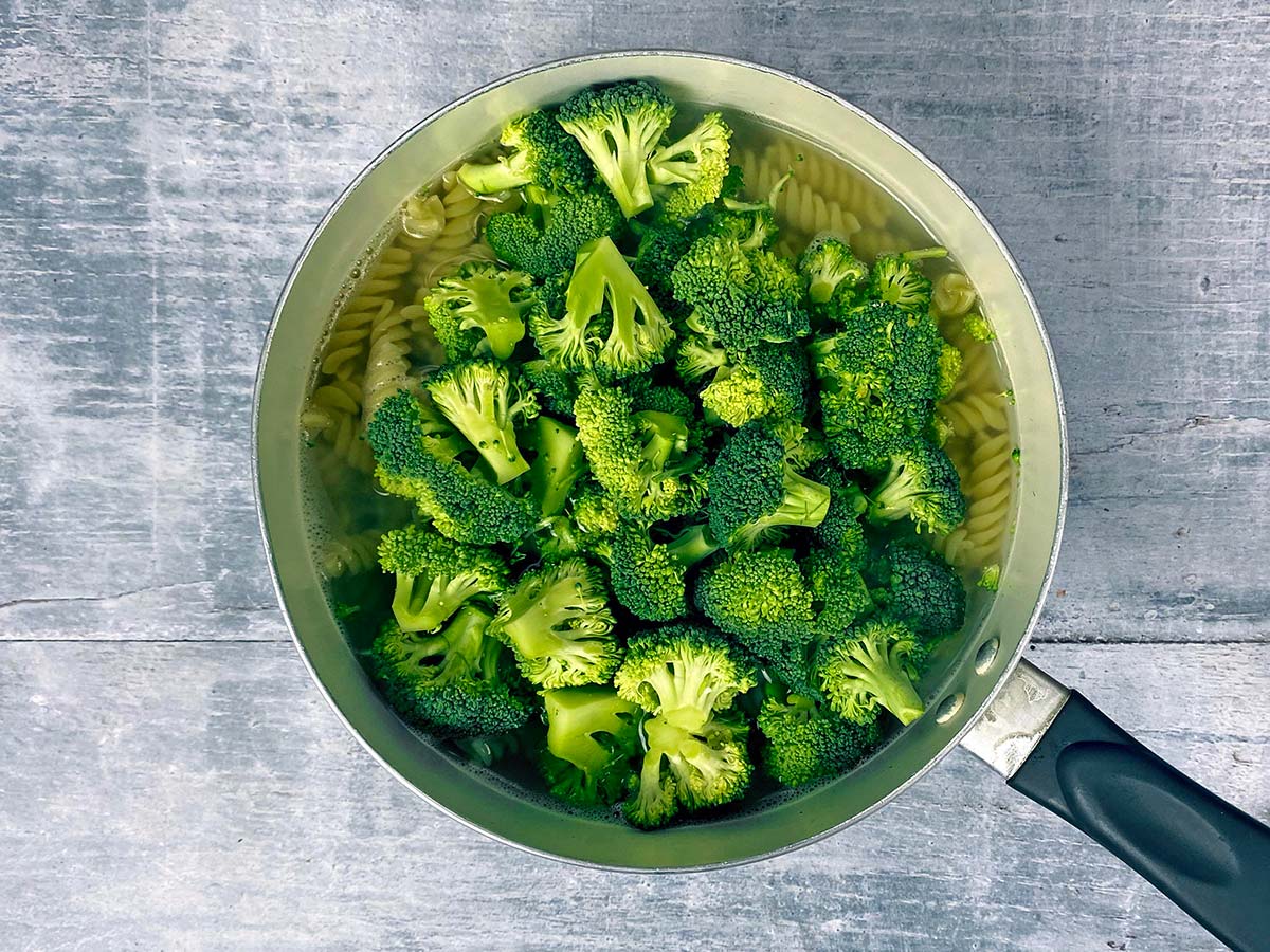 Broccoli florets added to the cooking pasta.