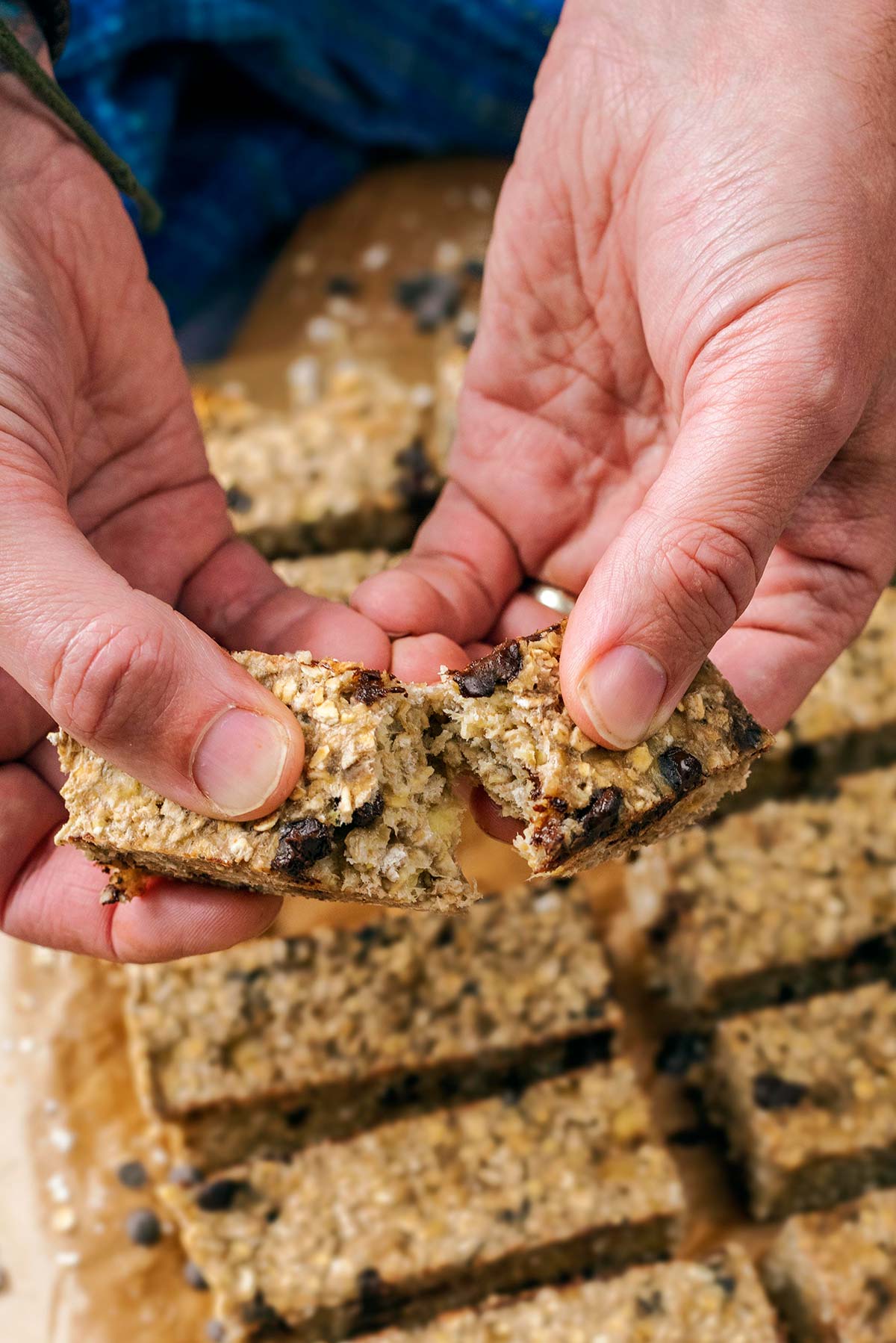 A pair of hands breaking a flapjack in half.
